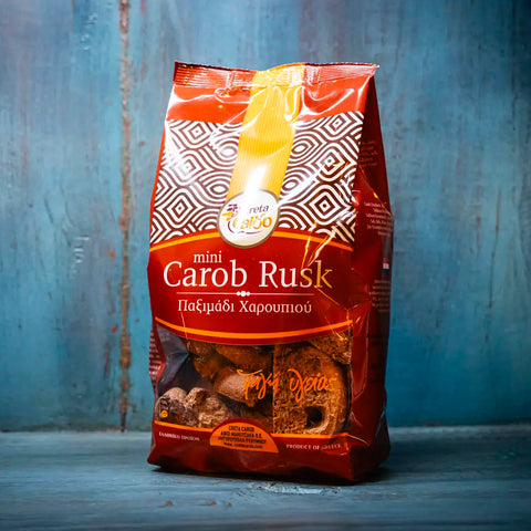 Carob Mini Rusks im blauen Ambiente – knusprige kleine Zwieback-Stücke mit natürlichem Johannisbrotgeschmack, ideal als mediterraner Snack.