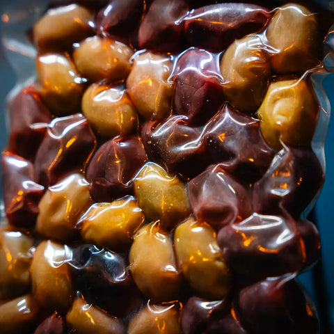 Fokus gemischte Oliven im blauen Ambiente – vielfältige Auswahl aromatischer mediterraner Oliven, perfekt als Snack oder für Salate.