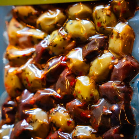 Fokus gemischte Oliven in mediterraner Marinade im blauen Ambiente – aromatische Vielfalt an mediterranen Oliven, perfekt für Salate und Feinschmecker.