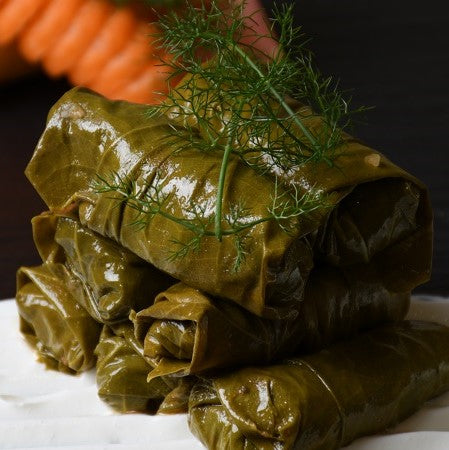Weinblätter angerichtet – frisch zubereitete, griechische Dolmades aus zarten Weinblättern mit aromatischer Reis-Kräuter-Füllung